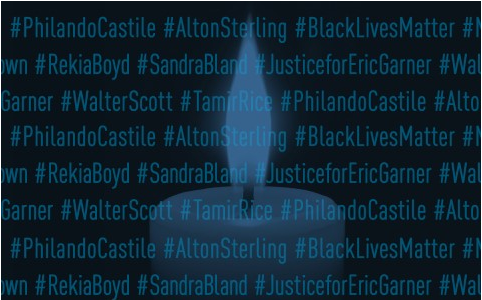 Candle burning behind hashtagged names of victims of police shootings
