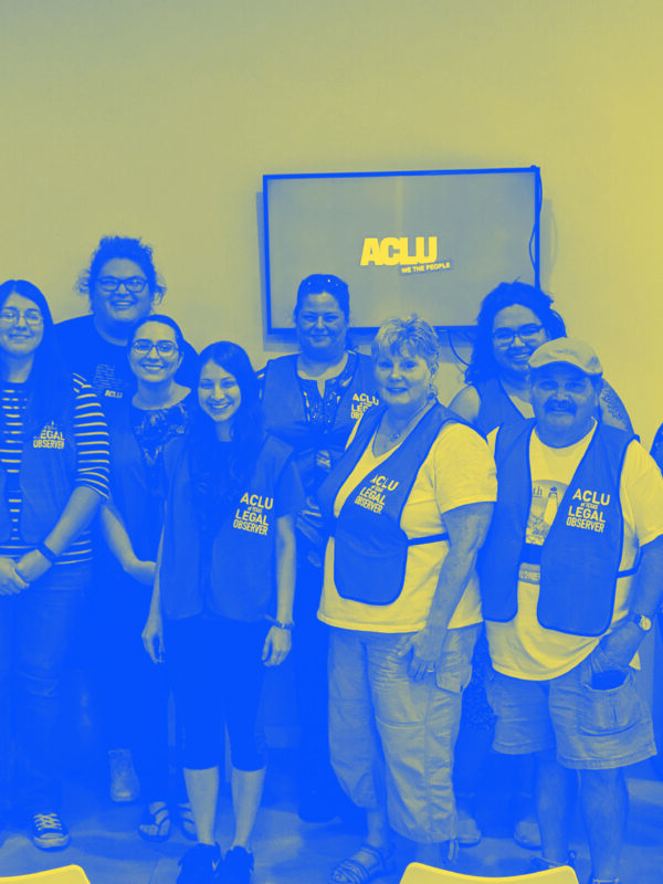 Image: A group people wearing vests that say 'ACLU of Texas Legal Observer' pose for the camera. Below them text reads Dallas Legal Observer Training / Union Coffee Dallas 3705 Cedar Springs Rd / November 16 | 2- 3:30pm.