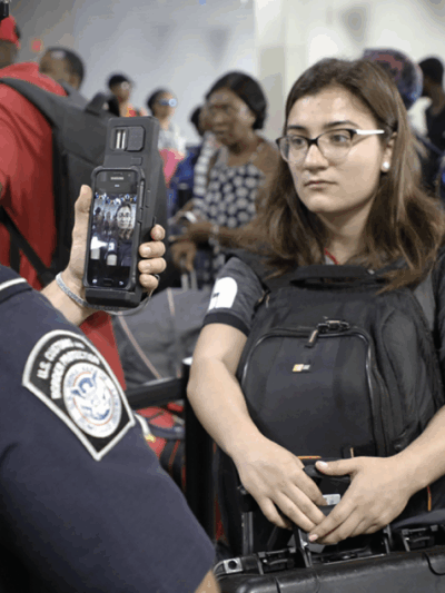 CBP agent scanning the face of a young woman using his smart phone