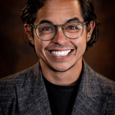 Image: A photo shows Adri Perez posing for the camera in front of a solid background.