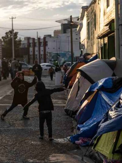 Two boys running around and playing outside of tents in Ciudad Juarez, Mexico.