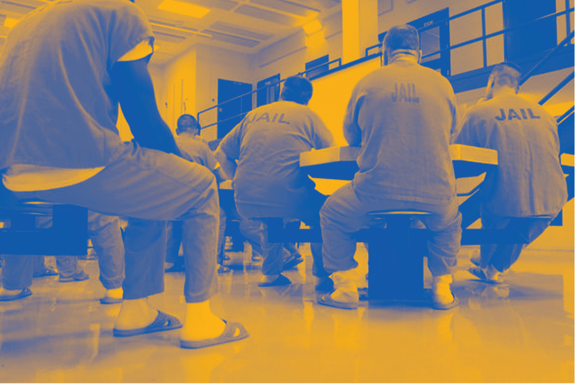 Image: A stylized photo shows men wearing uniforms that say "Jail" on their backs. They sit around tables in a carceral facility