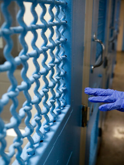 A gloved hand points to a holding cell in a Los Angeles jail.