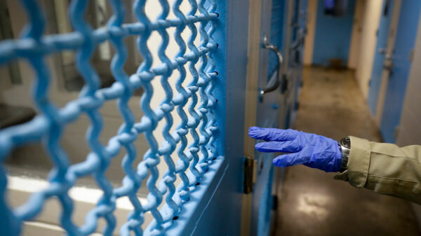 A gloved hand points to a holding cell in a Los Angeles jail.
