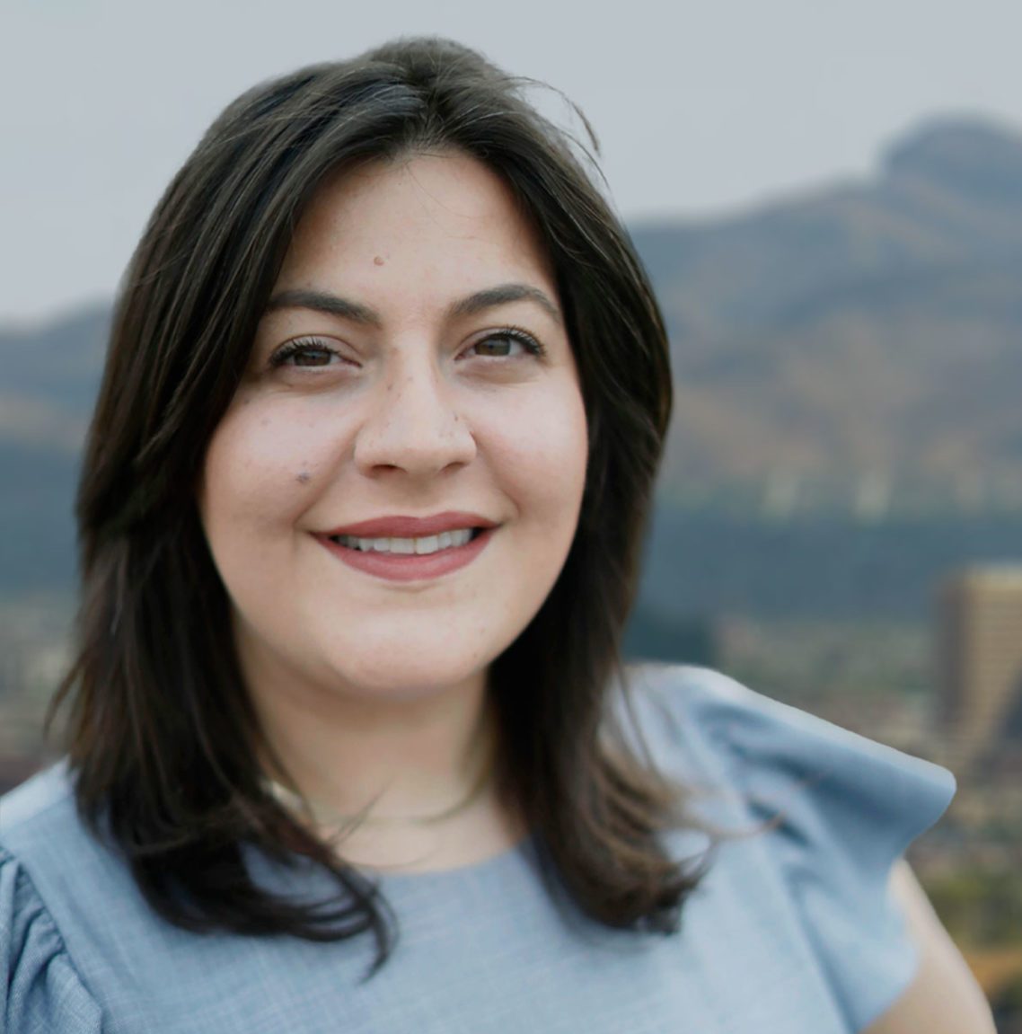 Photo: El Paso City Council member Alexsandra Annello smiles for a portrait outdoors. Visible behind her are mountains.
