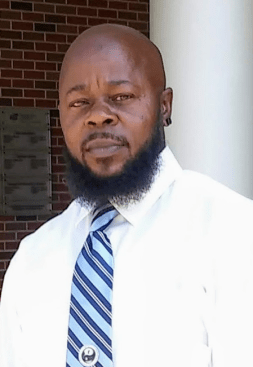 Photo: Carter Brown poses for a photo outside of a building. Brick and a white column are visible behind him.