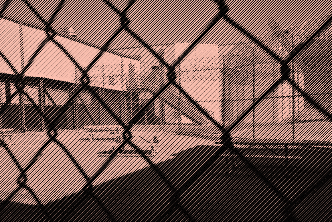 Image: A stylized photo shows an outdoor area of a detention center with some benches and tables. It is surrounded by barbed wire and concertina wire. The camera's view is partially obscured by the barbed wire fencing.