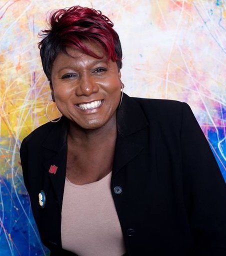 Photo: Monica Roberts poses for a photo in front of a brightly colored backdrop.