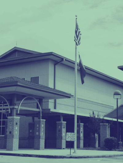 Image: A stylized photo shows a school building with a flag pole in front.