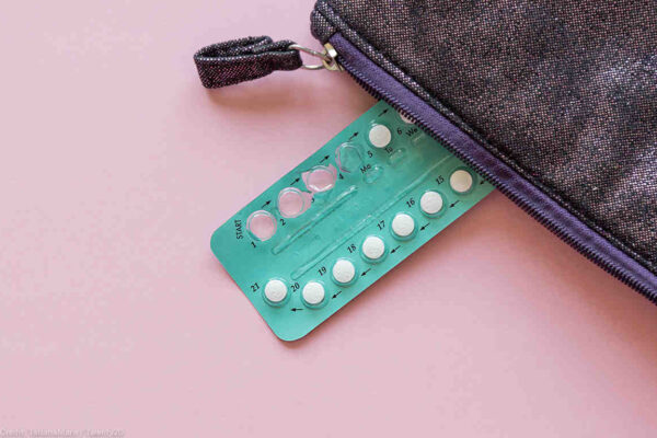 Photo: An aluminum packet of small circular pills has a few missing, the spots where they were punched out of the aluminum visible. The packet peacks out of a zipper pouch.
