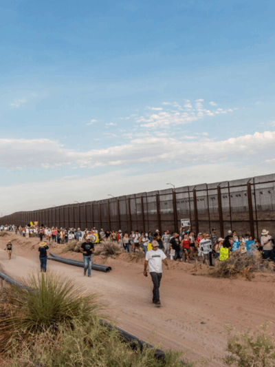 Photo: Immigrants' rights supporters lined up to march alongside a stretch of Border Wall in El Paso, Texas