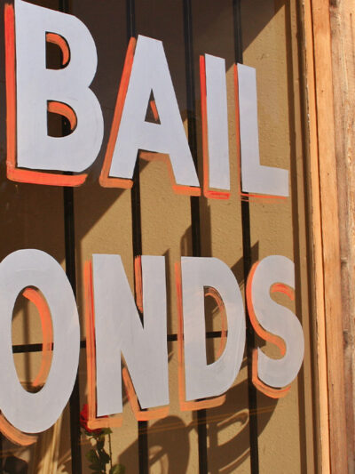 Image of a hand painted sign that reads "Bail Bonds" on a window