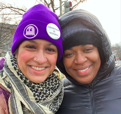 Photo: Marie Khan and Moji Alawod-El lean in together and pose for a photo outside. They wear cold weather clothing.