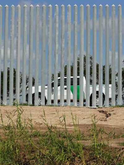 A CBP truck is seen through a border wall