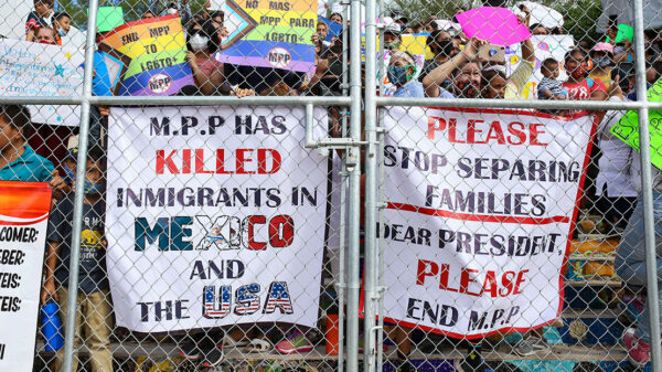 People press signs against a closed gate to the migrant encampment, asking then President Donald Trump to end the Migrant Protection Protocols during a rally at the encampment in Matamoros, Tamaulipas, Mexico on October 25, 2020.