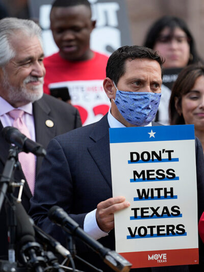 Rep. Trey Martinez Fischer, D-San Antonio, holds a sign that says, "Don't mess with Texas," as he and other Democratic caucus members join a rally on the steps of the Texas Capitol to support voting rights