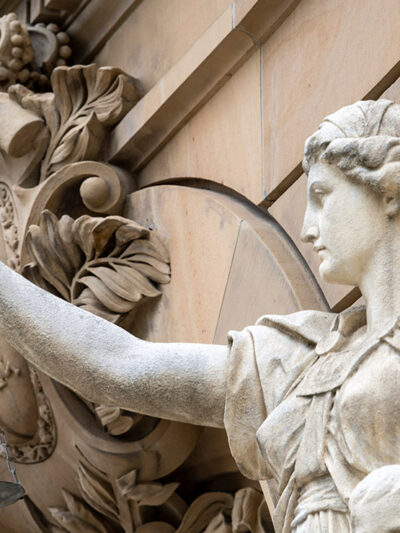 A statue of the goddess Justitia holds a pan of scales in front of the building of the district and regional court.