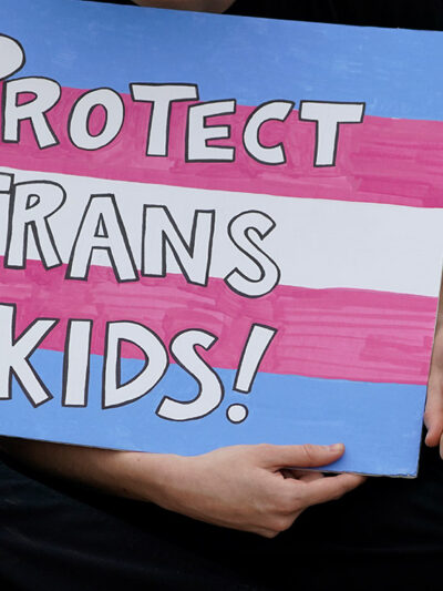 A protest sign reading "Protect Trans Kids."