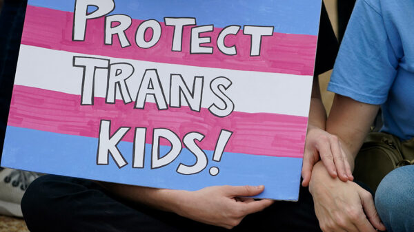 A protest sign reading "Protect Trans Kids."