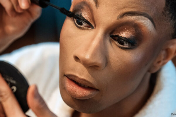 A drag performer applies mascara