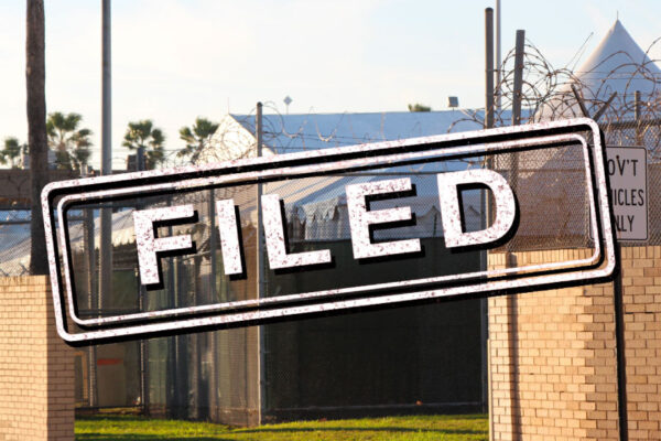 Exterior of migrant detention facility with the word "filed" stamped over the image.