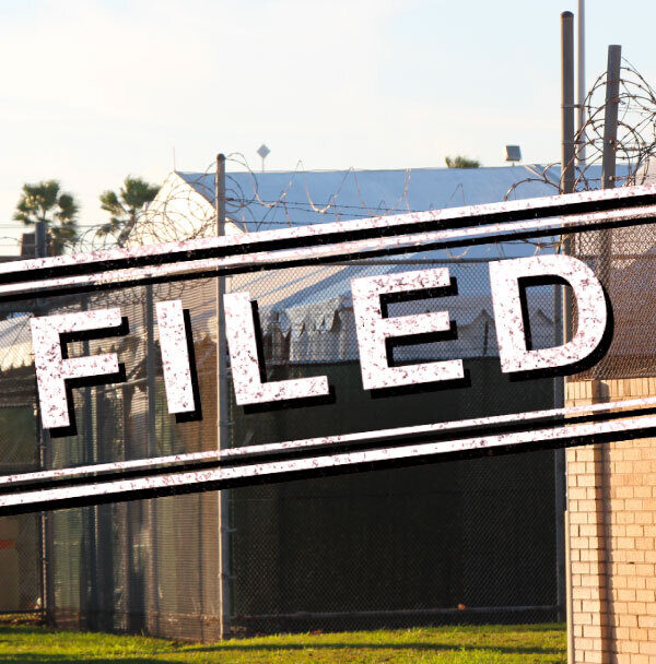 Exterior of migrant detention facility with the word "filed" stamped over the image.