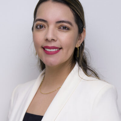 Image: A photo shows Cristina Soto posing for the camera in front of a solid background.
