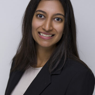 Photo: Savannah Kumar poses for a photo outdoors. She stands in front of a body of water with trees in the background.