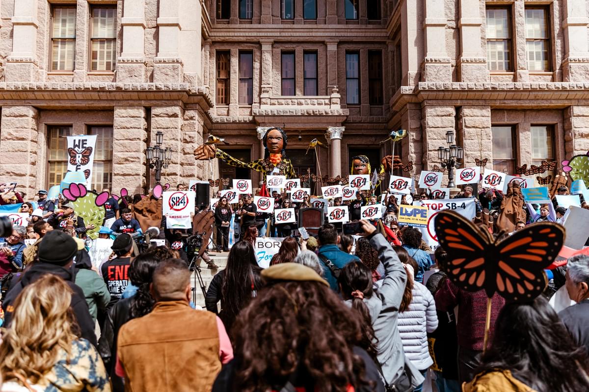 Giant puppets raise their hands at an immigrants' rights rally