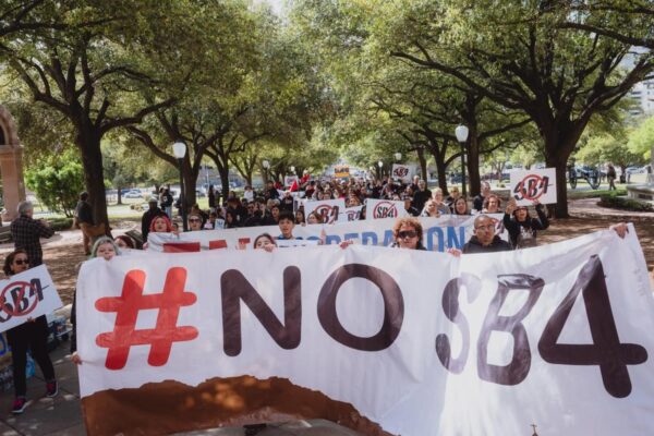 Photo by Christopher Lee of people marching to the Texas Capitol holding a "No S.B. 4" banner.