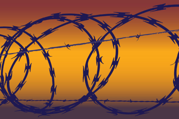 Barb wire in front of a yellow and orange hued background