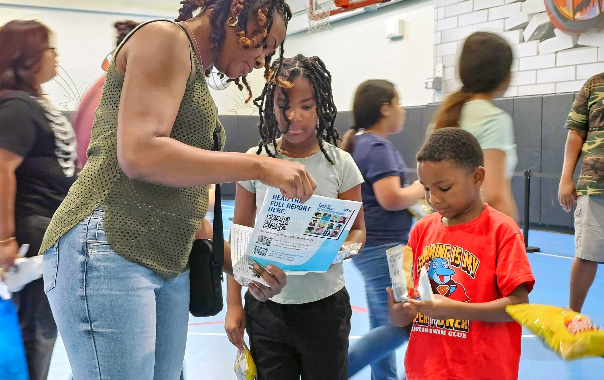 An adult and two children learn about the Students' Rights Hub