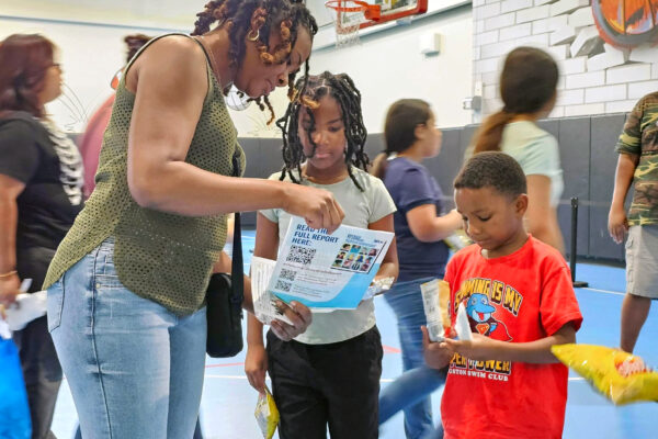 An adult and two children learn about the Students' Rights Hub