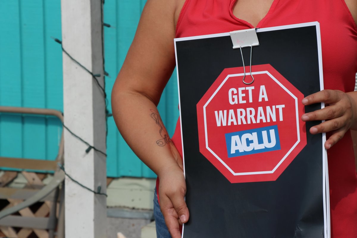 Image of a woman carrying a Get a Warrant ACLU sign