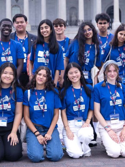 A group of high school students wearing blue shirts reading "DISSENT IS PATRIOTIC" pose for the camera.