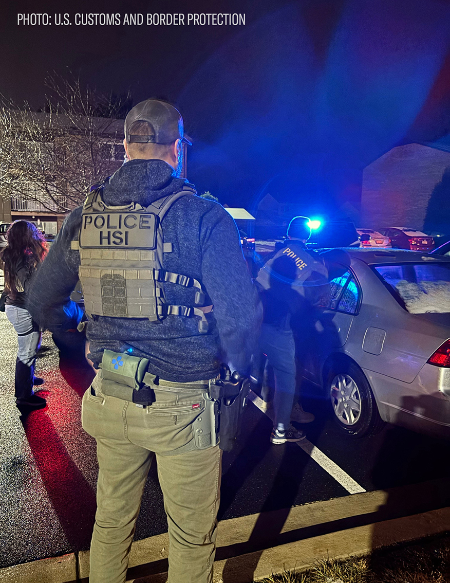 image of an ice agent from behind with his vest reading POLICE HSI