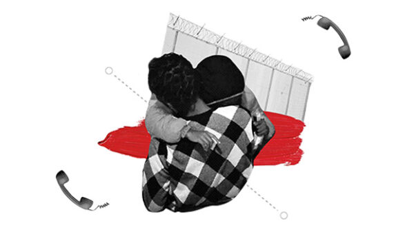 Shows two pwoplw hugging with a fence and a phone is the background