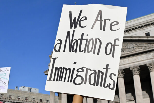 Two signs are held up during the May Day March In Manhattan, New York on May 1, 2025. The largest of the signs is in the foreground and reads"We Are a Nation of Immigrants," while the smaller in the background reads, " WE ARE ALL (EXCEPT NATIVE...