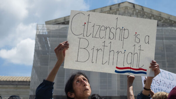A demonstrator looks up at her sign (which reads "Citizenship is a Birthright") during a rally outside the Supreme court building demanding the court uphold the 14th Amendment to the U.S. Constitution.