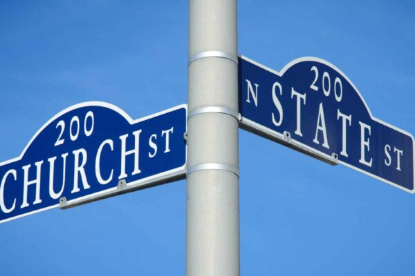 Photo of a pole with two street signs pointing in different directions, one that says "Church" and the other that says "State."