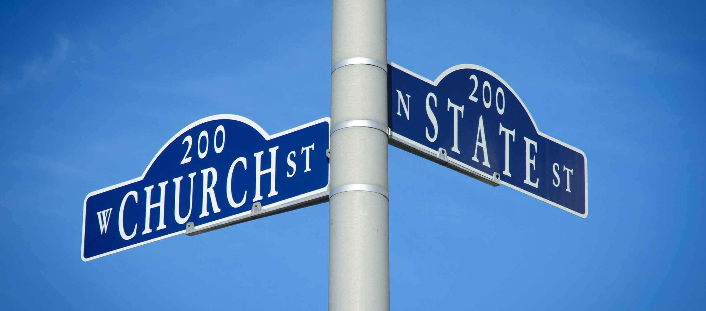 Photo of a pole with two street signs pointing in different directions, one that says "Church" and the other that says "State."