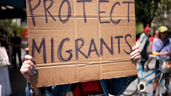 Photo of a cardboard protest sign that reads "PROTECT MIGRANTS" in all caps.
