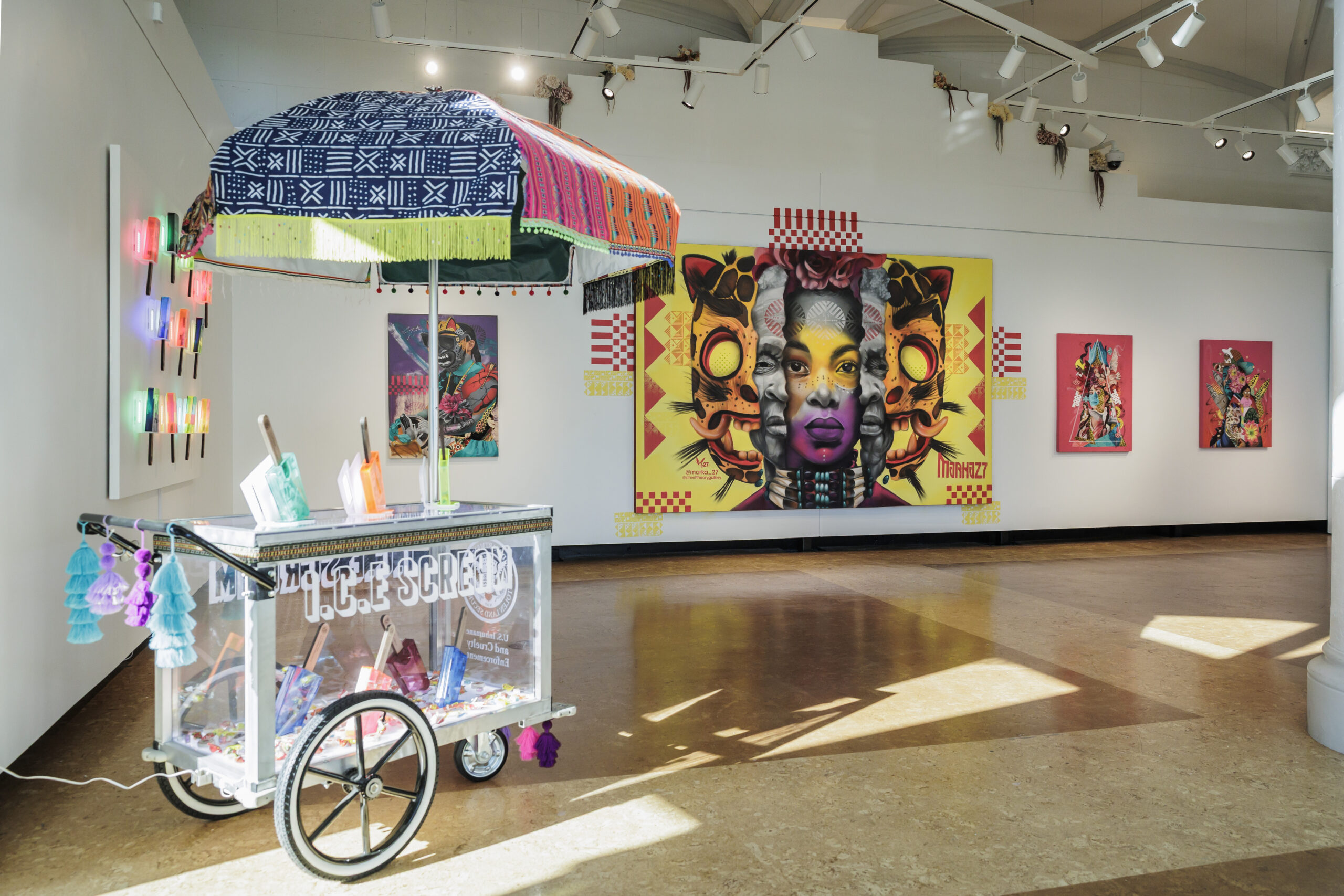 MARKA27's colorful art exhibit includes a vibrant popsicle cart in the foreground and eclectic, large-scale modern artwork on the walls.