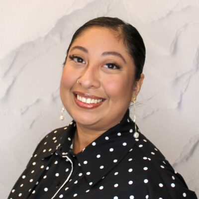 Image of Cecilia smiling wearing a black and white polka dot shirt.