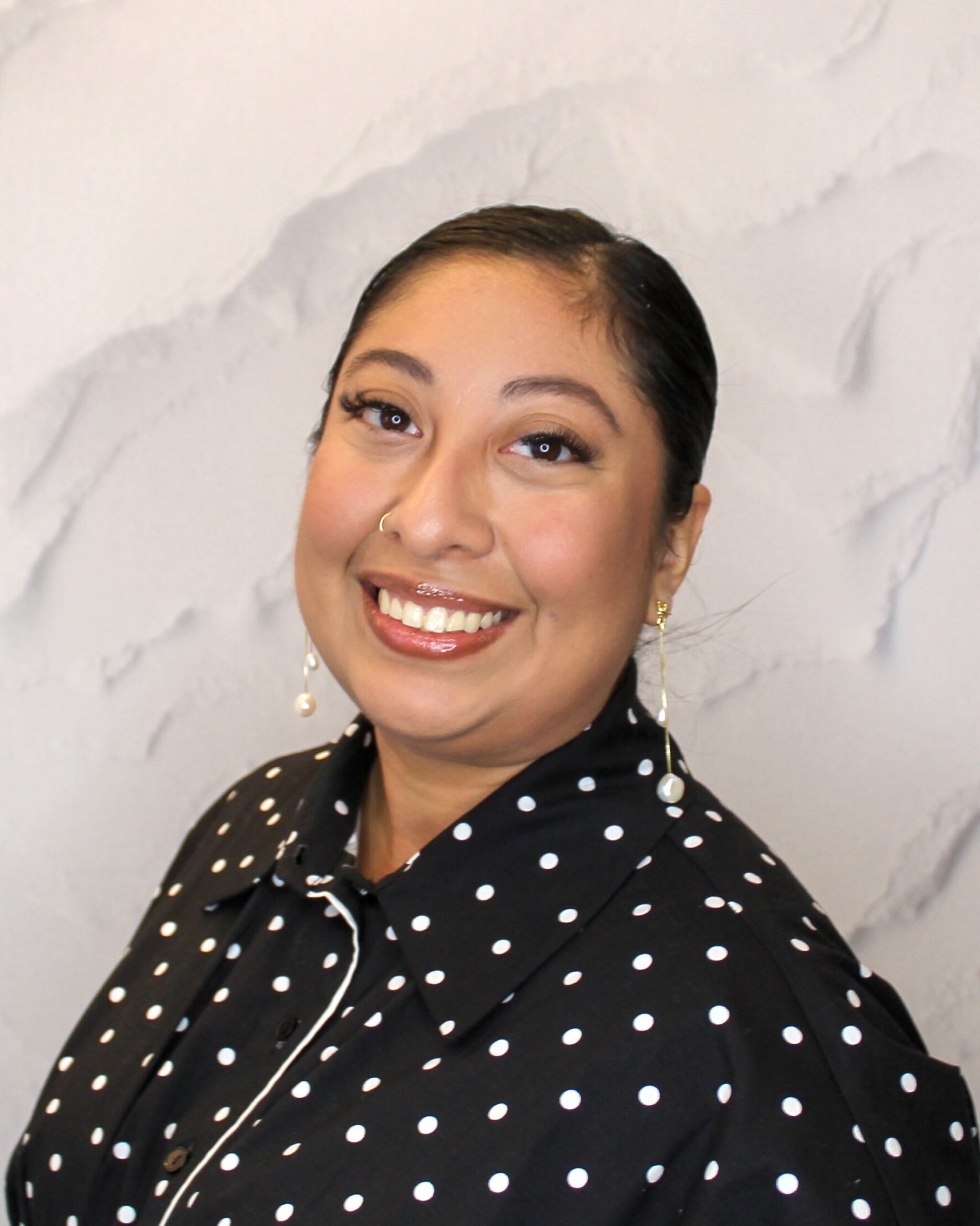 Image of Cecilia smiling wearing a black and white polka dot shirt.