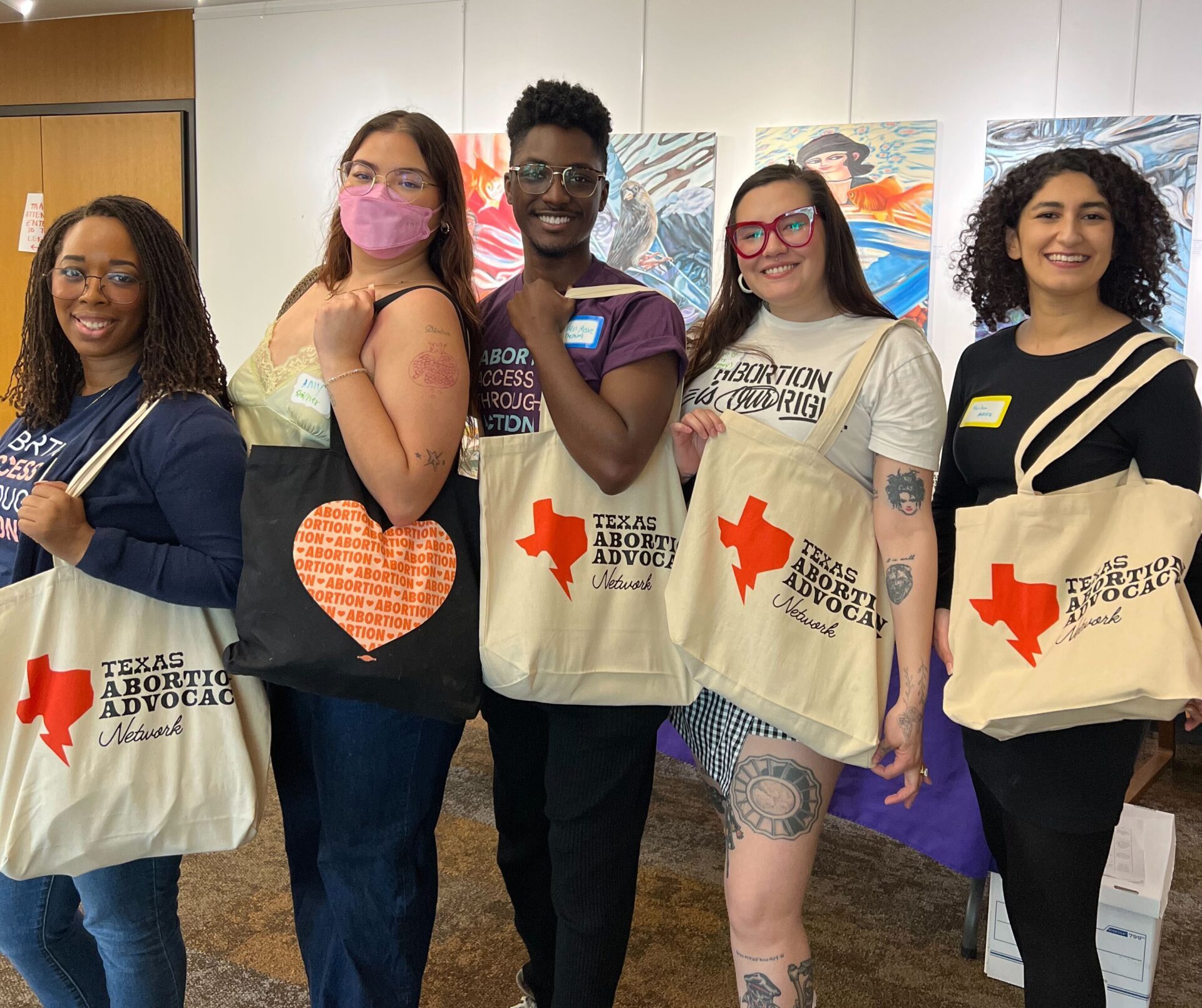 image of 5 taan members holding tote bags that read Texas Abortion Advocacy Network