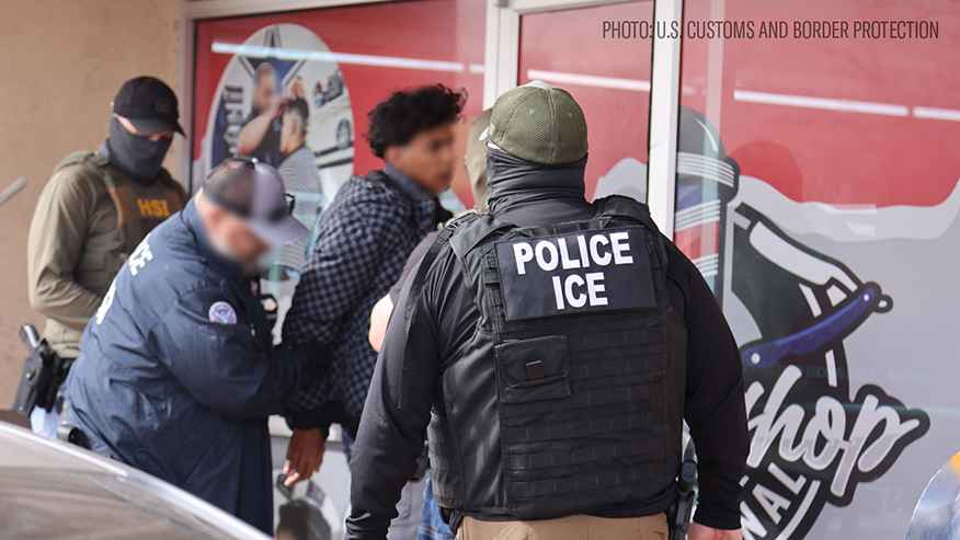 image of an ice agent from behind with his vest reading POLICE ICE