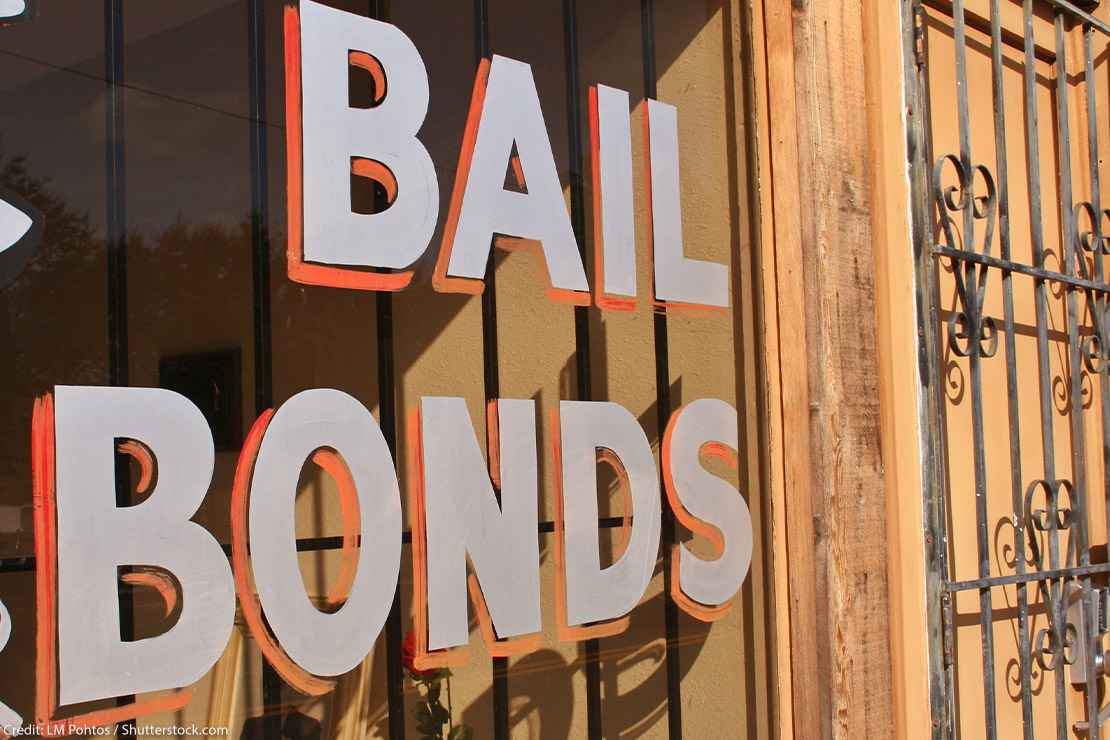Image of a hand painted sign that reads "Bail Bonds" on a window