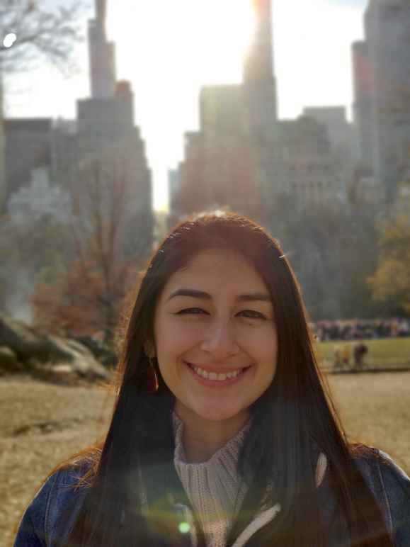 an image of Sarah Cruz smiling with a cityscape background behind her