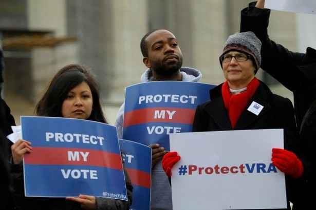 Photo: People gather, wearing cold-weather clothes, in front of the Supreme Court. They hold printed signs that say 'Protect My Vote" or "#ProtectVRA."